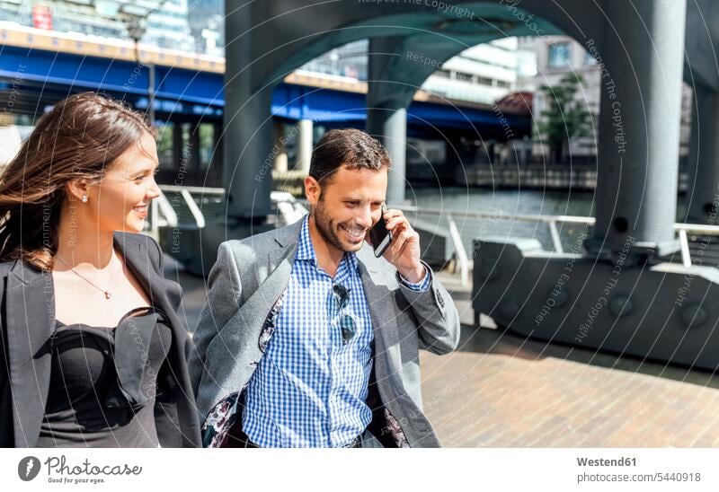 Smiling businessman on the phone and businesswoman in the city mobile phone mobiles mobile phones Cellphone cell phone cell phones commuter commuters