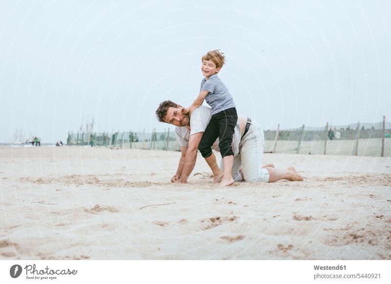 Father and little son playing together on the beach sons manchild manchildren beaches father pa fathers daddy dads papa family families people persons