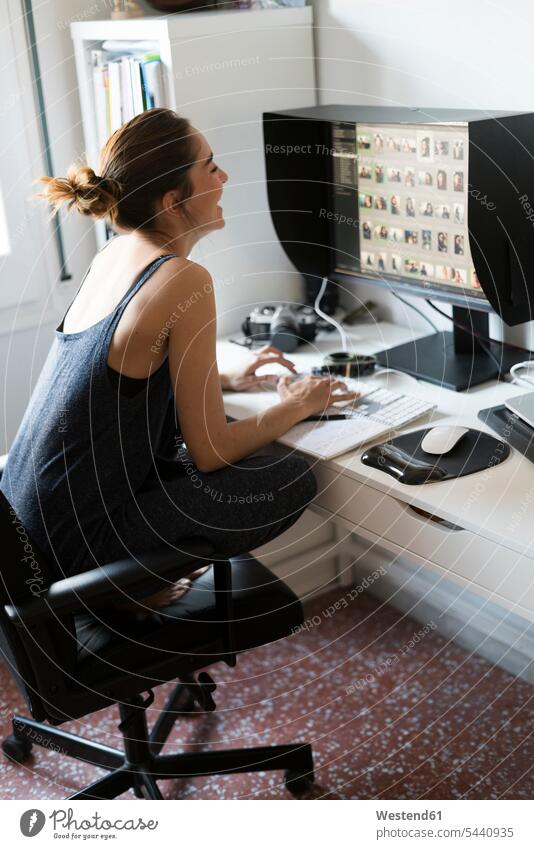 Female photographer editing images at desk photographs photos female photographer woman females women screen screens monitor monitors picture pictures
