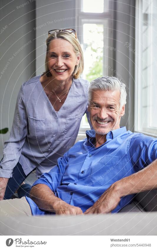 Portrait of smiling mature couple on couch at home portrait portraits relaxed relaxation sitting Seated smile twosomes partnership couples relaxing people