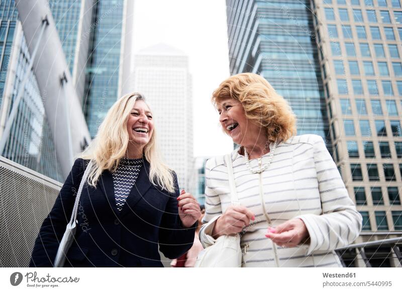 UK, London, two happy senior businesswomen in the city woman females Female Colleague laughing Laughter businesswoman business woman business women Adults