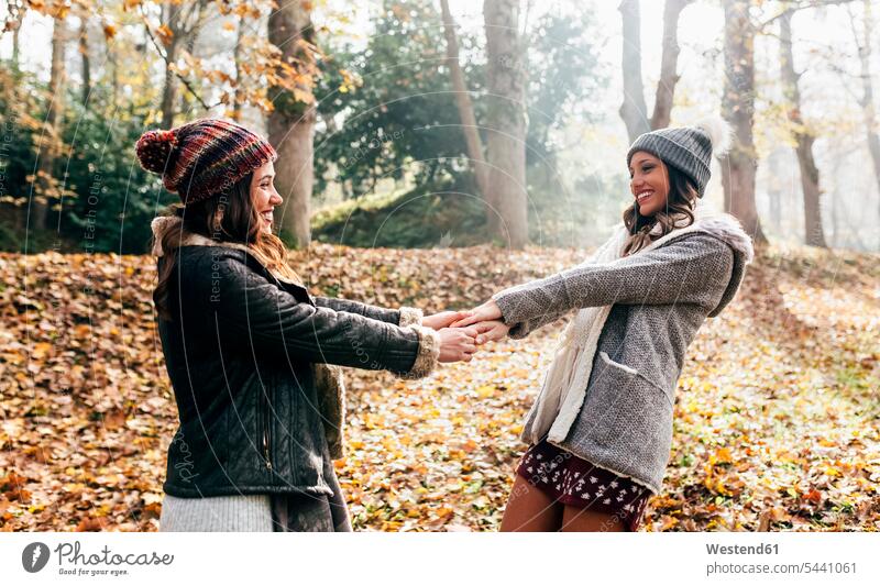 Two pretty women having fun in an autumnal forest woman females female friends beautiful Fun funny fall woods forests Adults grown-ups grownups adult people
