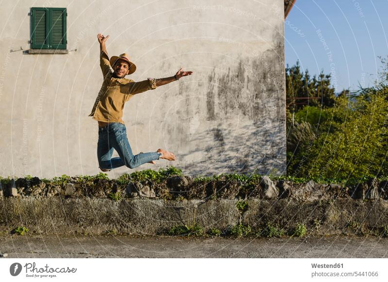 Happy young man jumping in the air jump in the air men males Leaping jumps Adults grown-ups grownups adult people persons human being humans human beings