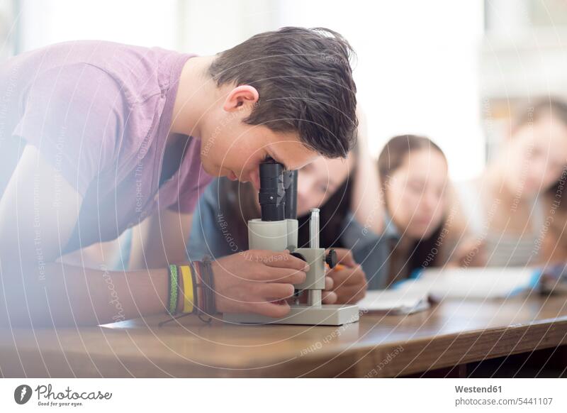 Science student in class looking through microscope pupils microscopes learning education school schools lesson lessons high school scrutiny scrutinizing