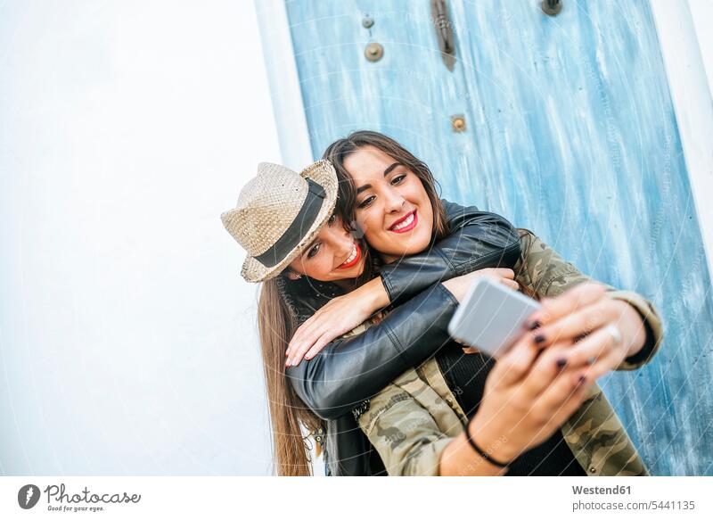 Two happy young women taking a selfie with a smart phone Selfie Selfies smiling smile mobile phone mobiles mobile phones Cellphone cell phone cell phones