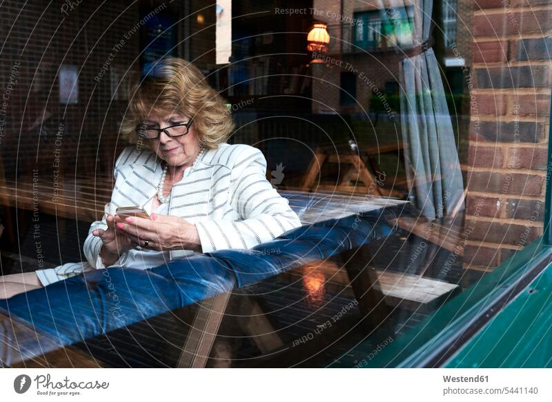 Senior businesswoman checking cell phone in a coffee shop mobile phone mobiles mobile phones Cellphone cell phones businesswomen business woman business women