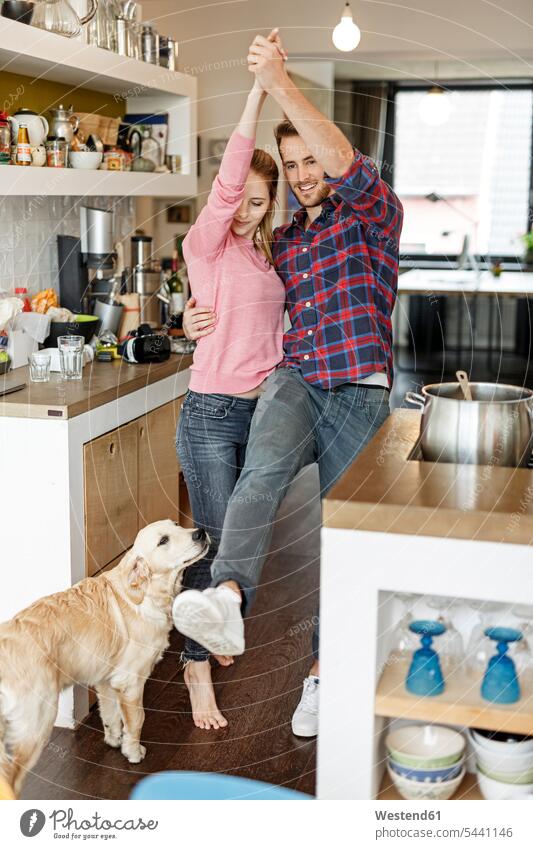 Young couple with dog dancing in the kitchen dogs Canine twosomes partnership couples dance pets animal creatures animals people persons human being humans