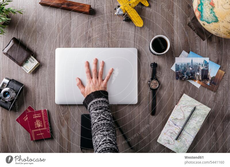 Overhead view of man's hand and travel items on table human hand hands human hands Travel laptop Laptop Computers laptops notebook camera cameras people persons