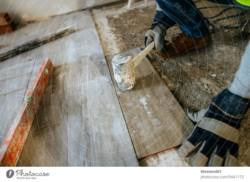 Close-up of construction worker placing flooring with a mallet construction site Building Site sites Building Sites construction sites builders working At Work