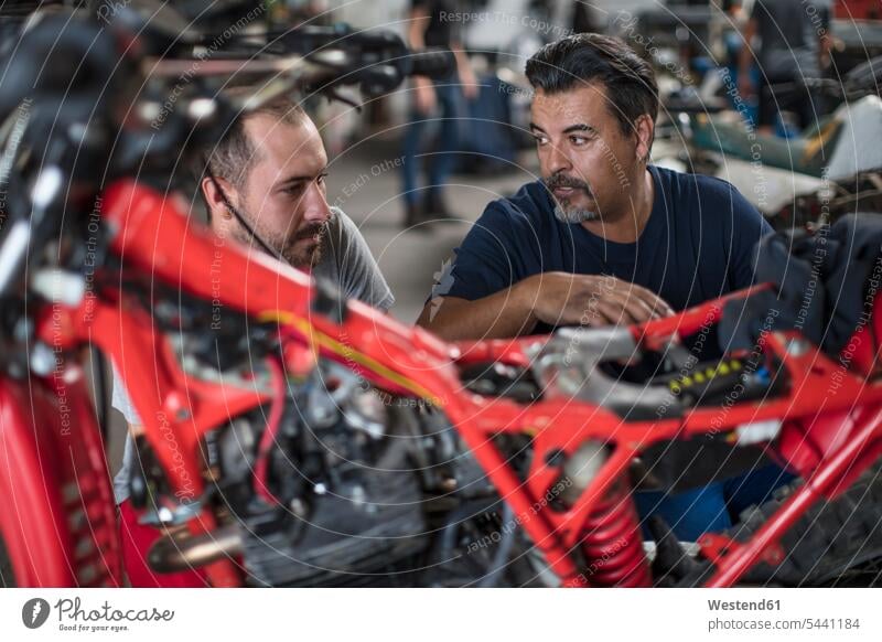 Two mechanics working on motorcycle in workshop together motorbike Motor Cycle repairing At Work colleagues mechanician repairman mechanicians mechanists