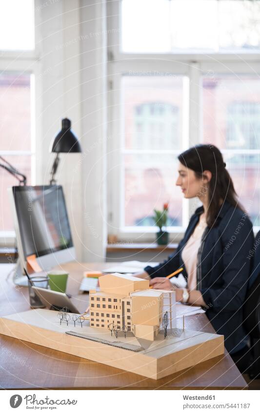 Architectural model and woman working at desk in office offices office room office rooms workplace work place place of work females women At Work Adults