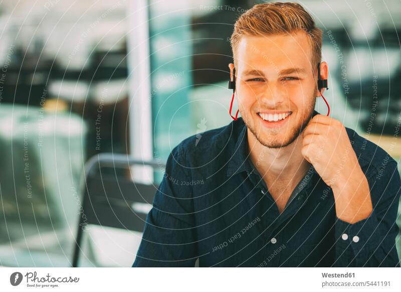 Young man wearing headset outdoors earphones ear phone ear phones men males headphones earbuds Earbud In-Ear Headphones ear bud Ear buds in-ear Adults grown-ups