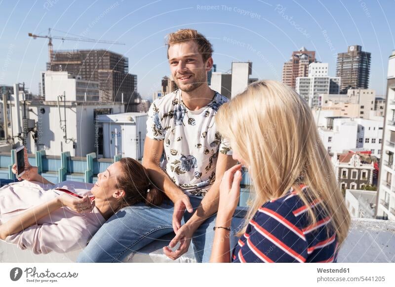 Friends meeting on a rooftop terrace in summer, woman using smartphone summer time summery summertime sharing share roof terrace deck friends Smartphone iPhone