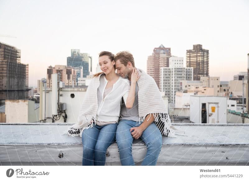 Romantic couple sitting on rooftop terrace, enjoying the view twosomes partnership couples flirting Flirtation Seated Falling In Love parapet balustrade