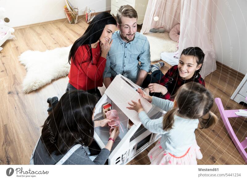 Parents and three daughters playing with doll house in nursery children's room Kids Room child's room Fun having fun funny family families smiling smile