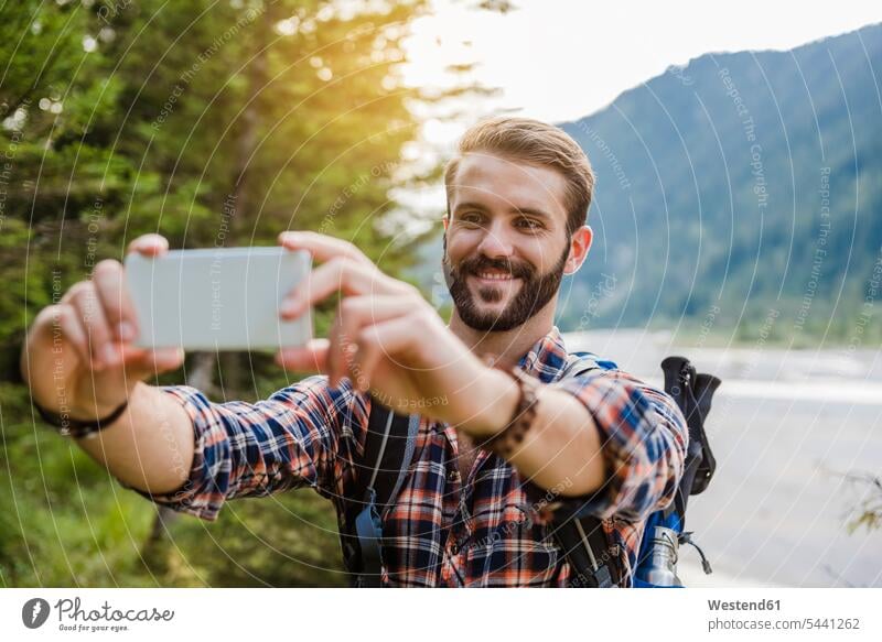 Portrait of smiling young hiker taking selfie with cell phone wanderers hikers portrait portraits Selfie Selfies hiking Smartphone iPhone Smartphones smile
