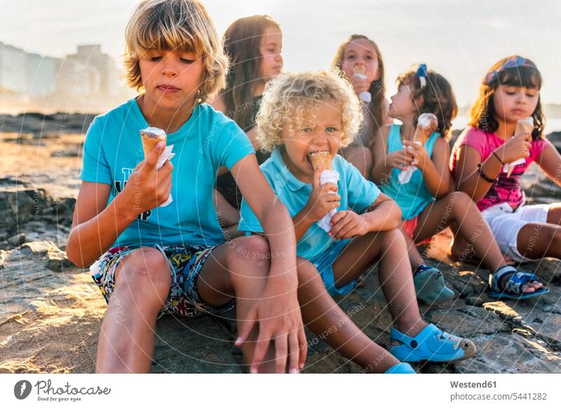 Group of six children eating icecream on the beach kid kids sitting Seated people persons human being humans human beings Sweet Food sweet foods food and drink