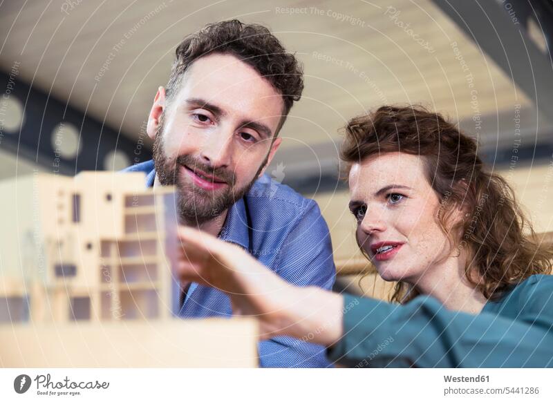 Man and woman discussing architectural model in office offices office room office rooms workplace work place place of work working At Work colleagues talking