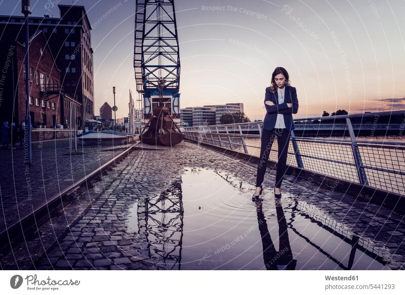 Businesswoman standing at wet inner harbor, thinking smart smart casual smart-casual Business Casual well dressed wetness serious earnest Seriousness austere