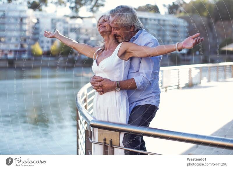 Senior couple taking a city break, embracing at a railing on the move on the way on the go on the road affectionate tender loving caressing City Break City Trip