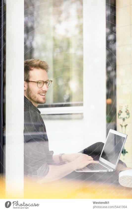 Portrait of smiling man using laptop at the window Laptop Computers laptops notebook men males portrait portraits windows smile computer computers Adults