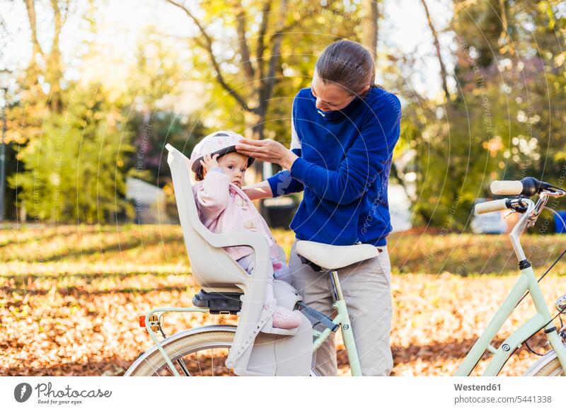 Mother and daughter riding bicycle, baby wearing helmet sitting in children's seat Child's Seat child seat child safety seat cycling helmet Bike Helmet