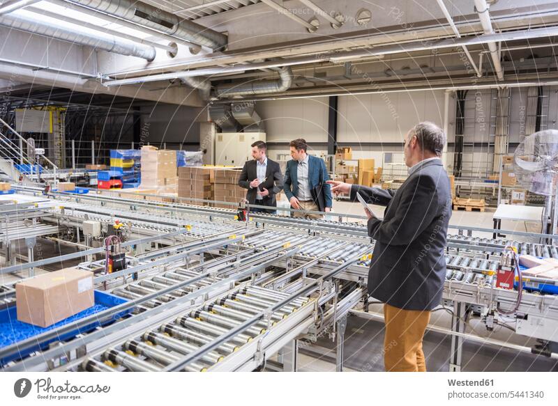 Three businessmen at conveyor belt in factory colleagues storehouse storage warehouse man males talking speaking working At Work Businessman Business man