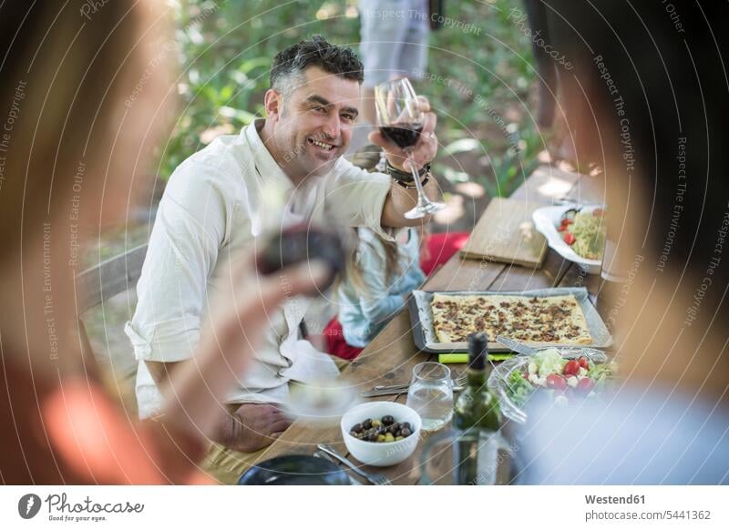 Friends and family having lunch in garden with red wine Wine friends toasting clinking cheers Red Wine Red Wines group of people Group groups of people