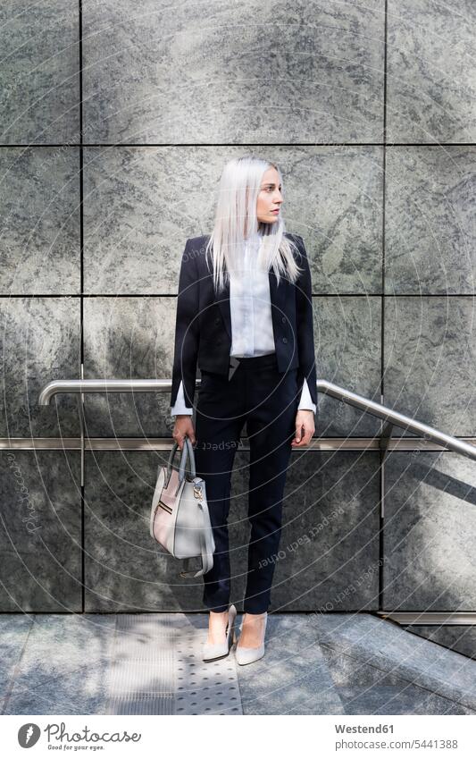 Young businesswoman standing outdoors looking around females women businesswomen business woman business women serious earnest Seriousness austere Adults