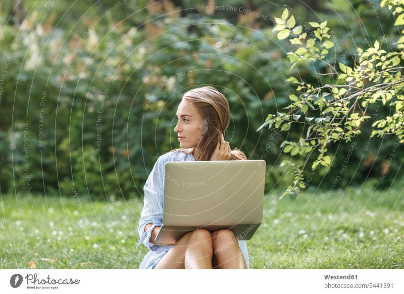 Young woman with laptop on a meadow looking sideways park parks Laptop Computers laptops notebook females women computer computers Adults grown-ups grownups