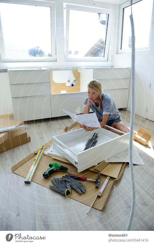 Woman reading assembly instructions at home DIY Doityourself Do it yourself Do-it-yourself woman females women setting up building up build up set up Adults