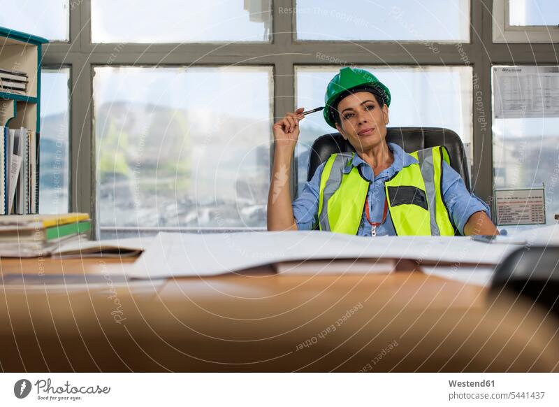 Female worker sitting in site office of quarry thinking mining Site plan blue collar worker workers blue-collar worker gravel pit plans working At Work