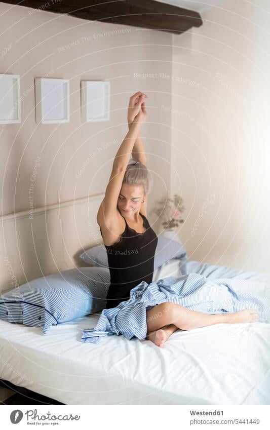 Young woman stretching in bed beds females women Adults grown-ups grownups adult people persons human being humans human beings eroticism sexuality awake alone
