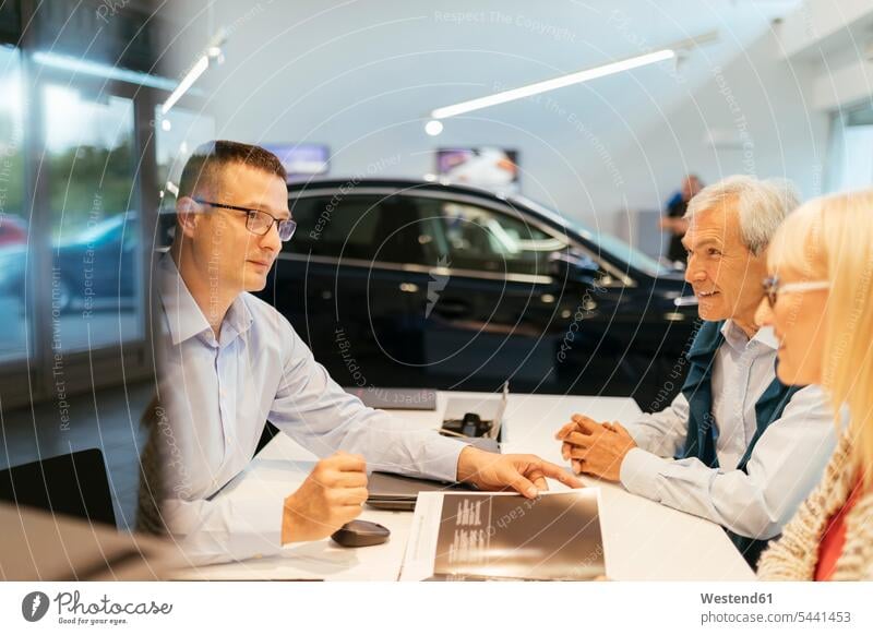 Salesperson advising couple in car dealership caucasian caucasian ethnicity caucasian appearance european young man young men 25-30 years 25 to 30