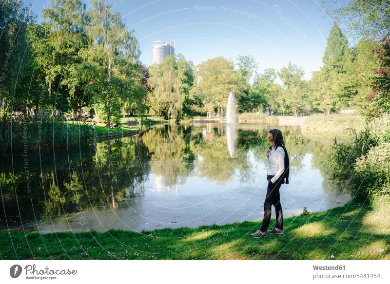 Businesswoman relaxing in the park parks Stroll walk businesswoman businesswomen business woman business women standing Pond Ponds females strolling walking