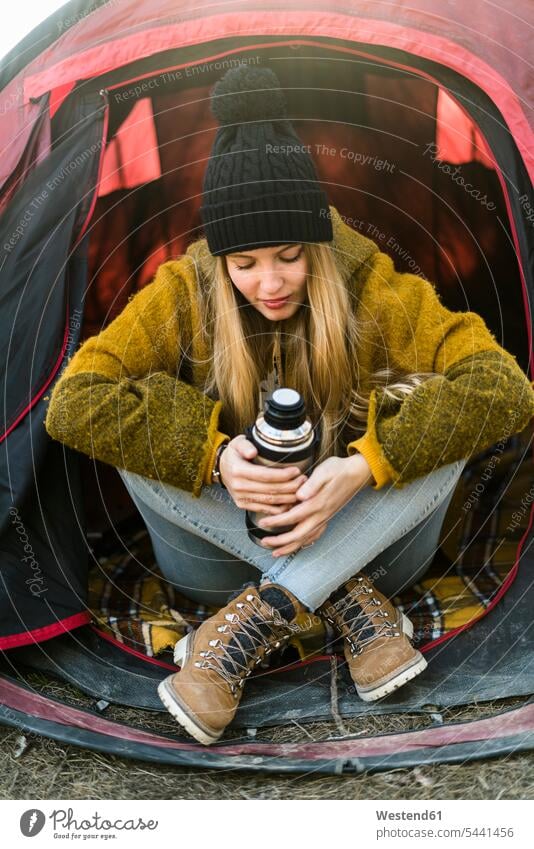 Young woman in tent sitting Seated females women Adults grown-ups grownups adult people persons human being humans human beings tents cap hats caps thinking