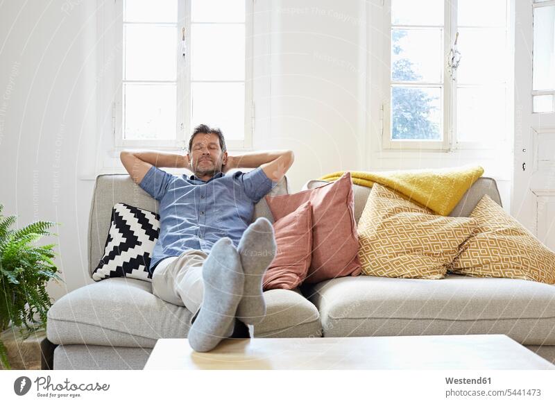 Man sitting on couch at home, relaxing man men males resting comfortable Seated relaxation relaxed Adults grown-ups grownups adult people persons human being