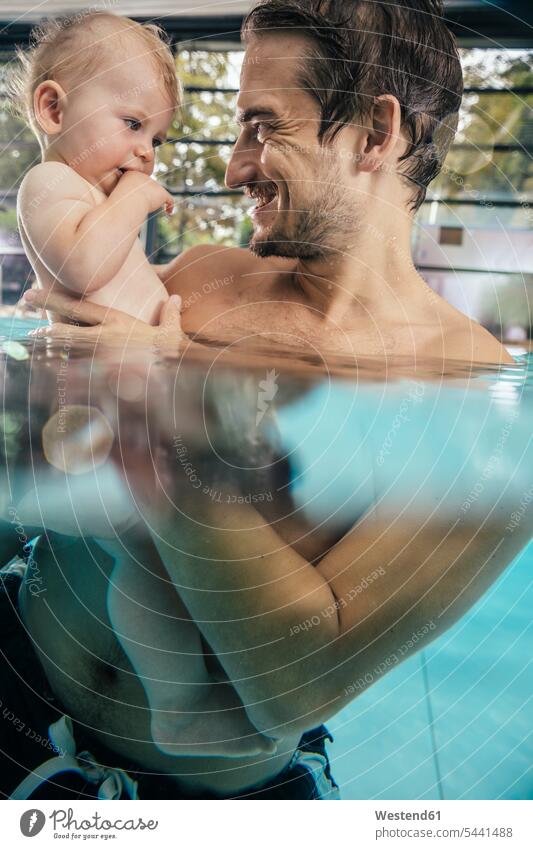 Father holding baby in indoor swimming pool infants nurselings babies swimming bath father pa fathers daddy dads papa smiling smile indoor swimming pools people