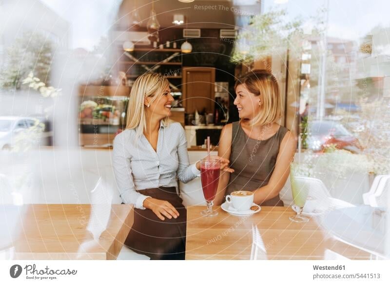 Two happy young women in a cafe Fun having fun funny talking speaking smiling smile female friends mate friendship mirrored Reflected mirroring reflection