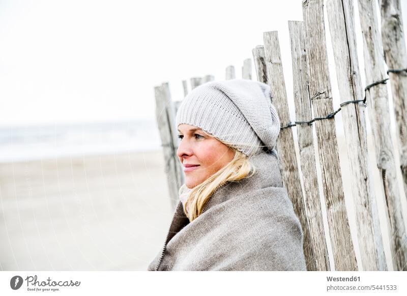 Smiling woman at fence on the beach beaches relaxed relaxation smiling smile females women relaxing Adults grown-ups grownups adult people persons human being