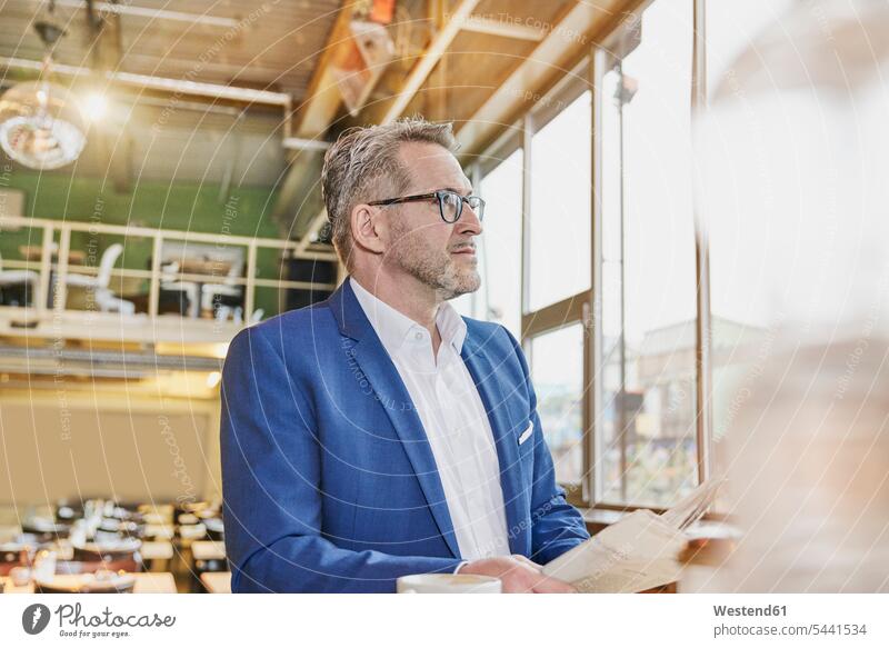 Mature businessman in cafe with newspaper looking sideways Businessman Business man Businessmen Business men business people businesspeople business world