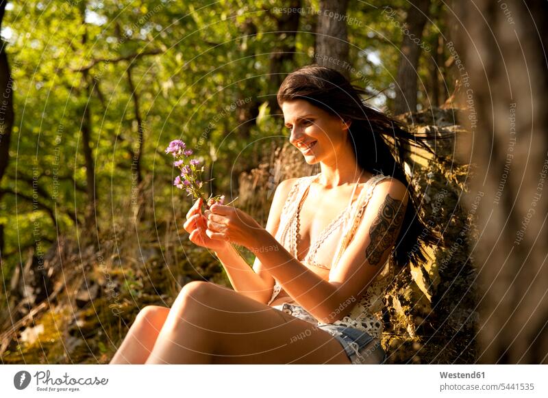 Young woman in forest binding bunch of flowers Flower Flowers woods forests relaxed relaxation females women relaxing Adults grown-ups grownups adult people