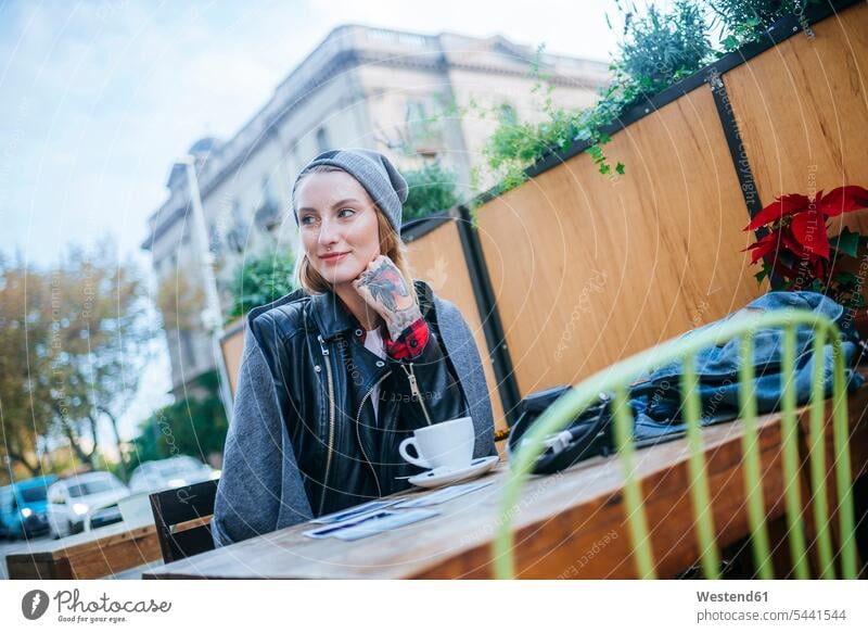 Young tattooed woman sitting in pavement cafe outdoor cafes females women Adults grown-ups grownups adult people persons human being humans human beings Coffee