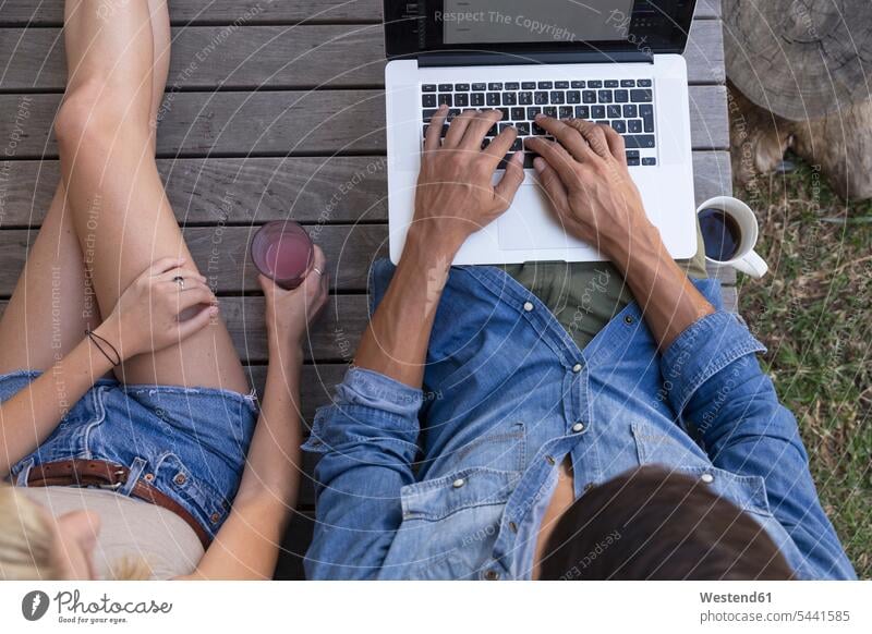 Overhead view of man sitting on terrace using laptop next to woman terraces Laptop Computers laptops notebook couple twosomes partnership couples Seated