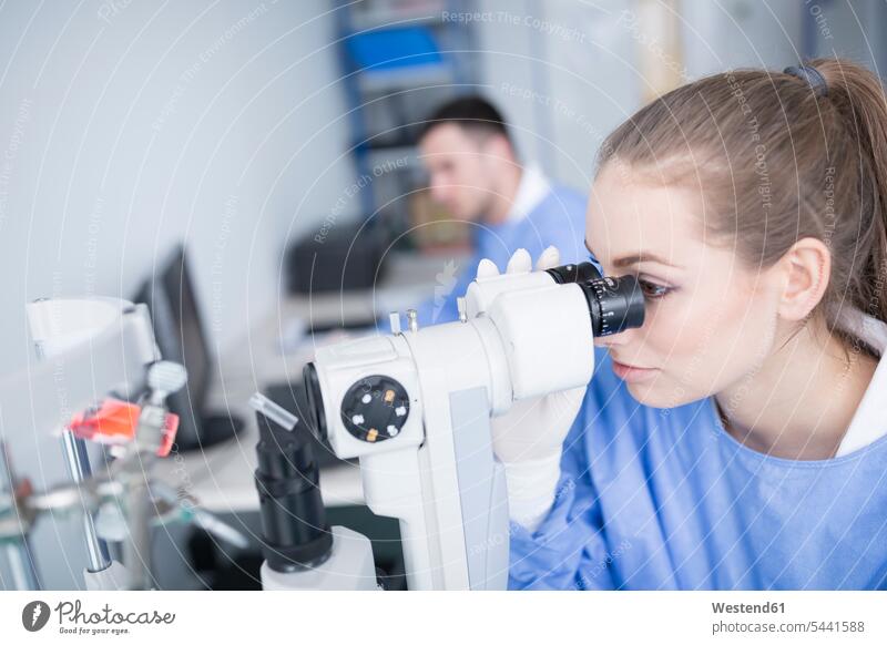 Lab technician looking through microscope laboratory technician Lab Tech working At Work examining checking examine microscopes view seeing viewing science