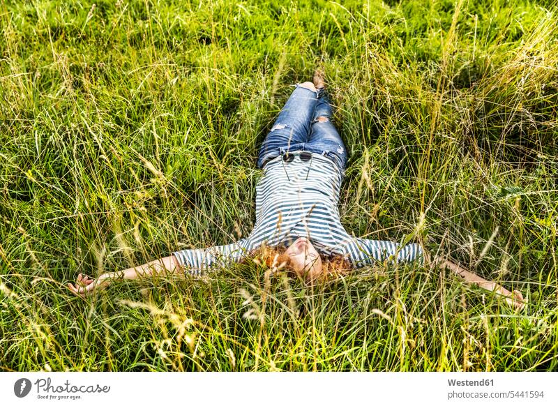 Young woman relaxing on a meadow females women meadows lying laying down lie lying down Adults grown-ups grownups adult people persons human being humans