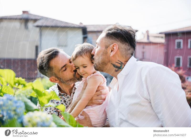 Gay couple kissing their daughter in the garden daughters kisses twosomes partnership couples gay gay men gay man homosexual men homosexual man child children