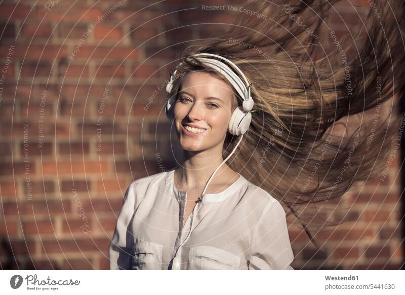 Portrait of happy woman with headphones and blowing hair females women portrait portraits headset Adults grown-ups grownups adult people persons human being