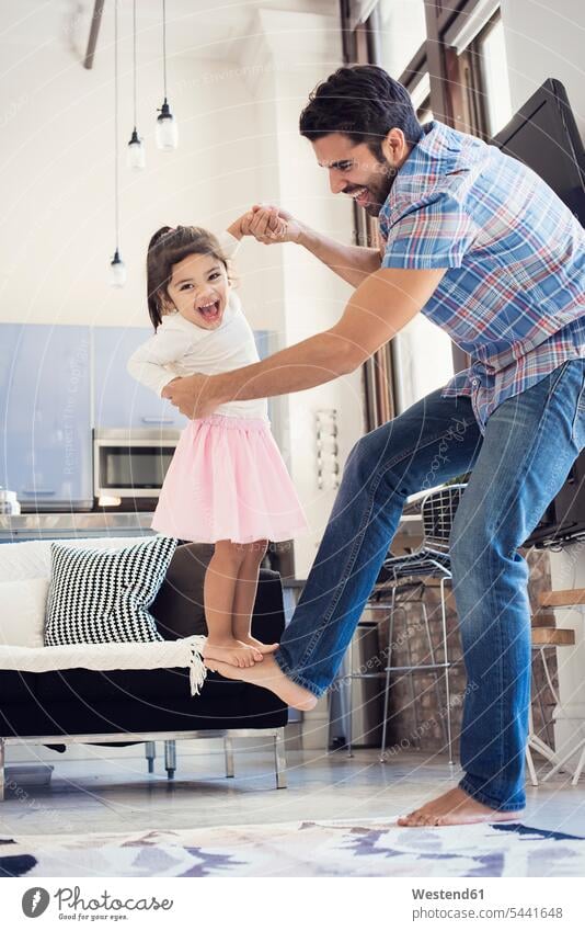 Father balancing his daughter on his foot human foot human feet carefree messing about silly silliness home at home daughters balance father pa fathers daddy