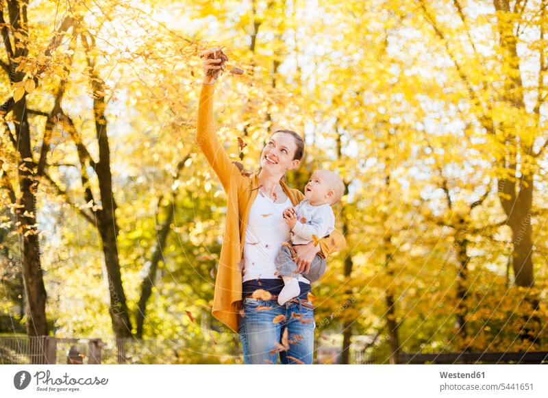 Mother and baby girl having fun with leaves in autumn infants nurselings babies baby girls female mother mommy mothers mummy mama fall Fun funny Leaf Leaves